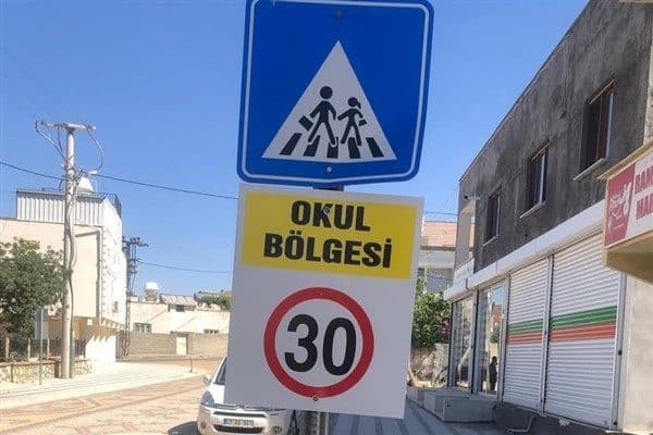Belediye ekipleri, yol boyunca hız sınırını gösteren tabelaları yerleştirirken, kurallara